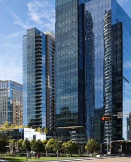 A tall, glass, blue office building in a city.